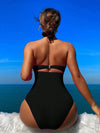 Crisscross halter one-piece swimsuit with wide-brimmed hat, showcasing elegant vacation style. Enjoy the sun, savor the sea view