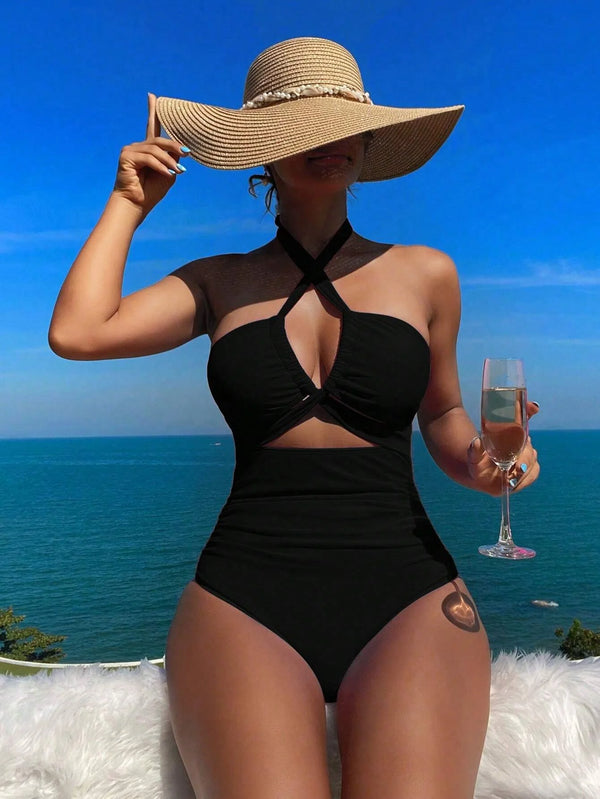 Crisscross halter one-piece swimsuit with wide-brimmed hat, showcasing elegant vacation style. Enjoy the sun, savor the sea view