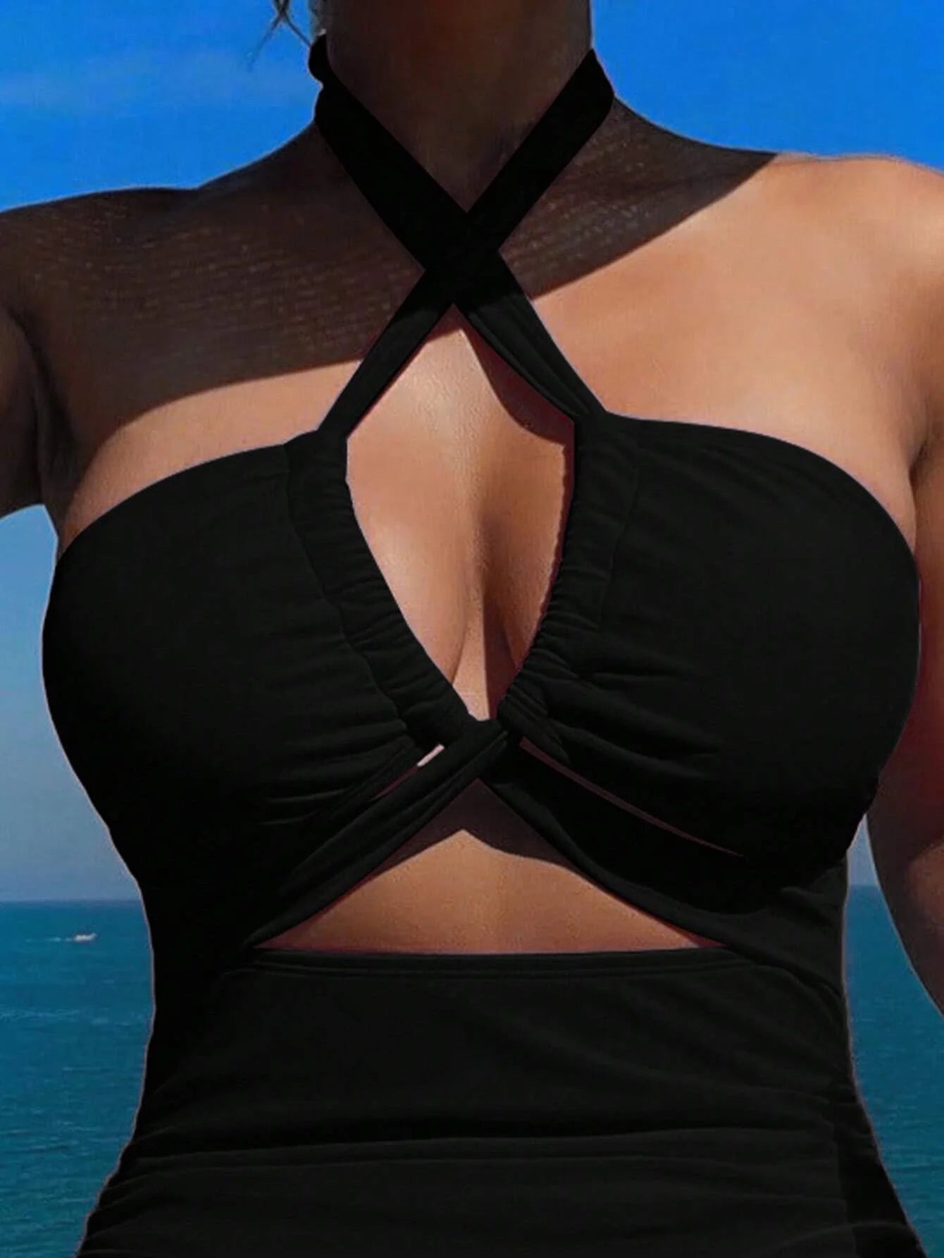 Crisscross halter one-piece swimsuit with wide-brimmed hat, showcasing elegant vacation style. Enjoy the sun, savor the sea view
