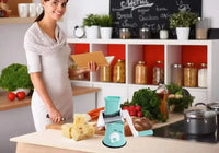 Woman using a manual rotary vegetable slicer in a vibrant kitchen filled with fresh vegetables and cheese.