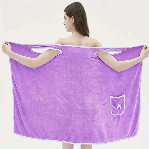Adult wearing a purple wearable bath towel with bowknot design, featuring pockets and quick-drying coral velvet material.