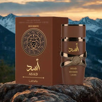 Lattafa Asad Bourbon Eau De Parfum 3.4 oz with box, set against a mountainous backdrop, showcasing its elegant design.
