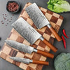 Set of four Japanese kitchen knives on a wooden cutting board, showcasing sharp stainless steel blades and wooden handles.